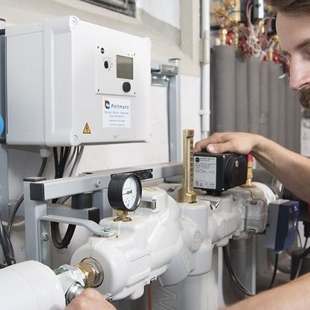 Ein Mann arbeitet an einem Wasserheizer und führt Wartungsarbeiten durch.