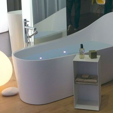 Zeitgemäße Badewanne mit strahlend weißer Oberfläche und sanfter Lichtquelle, die Gemütlichkeit ausstrahlt.