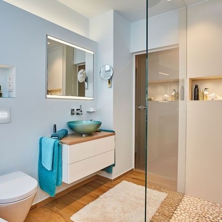 Badezimmer mit gläserner Duschkabine und Toilette, modern und hell gestaltet, bietet eine einladende Atmosphäre.