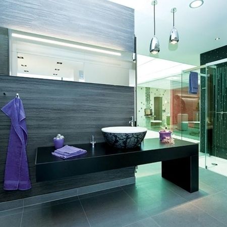 Modernes Badezimmer mit schwarzem Waschbecken und lila Handtüchern, stilvoll und elegant gestaltet.