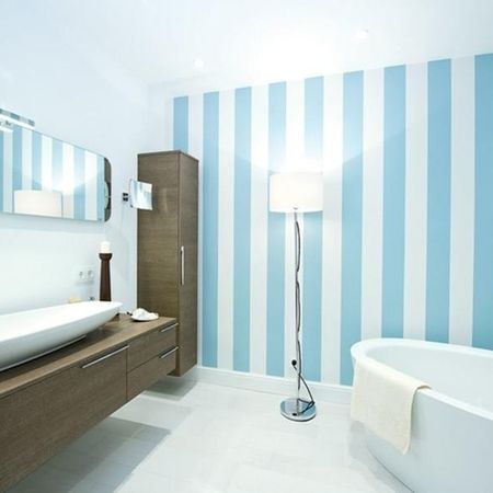 Modernes Badezimmer mit blauen und weißen gestreiften Wänden, das eine frische und einladende Atmosphäre schafft.