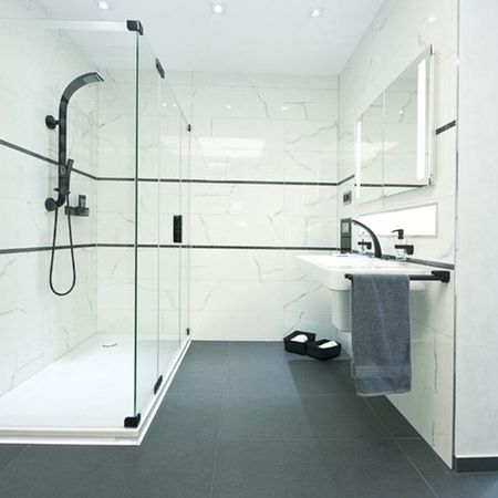 Modernes Badezimmer mit gläserner Duschkabine, elegantes Design und helle Farben schaffen eine einladende Atmosphäre.